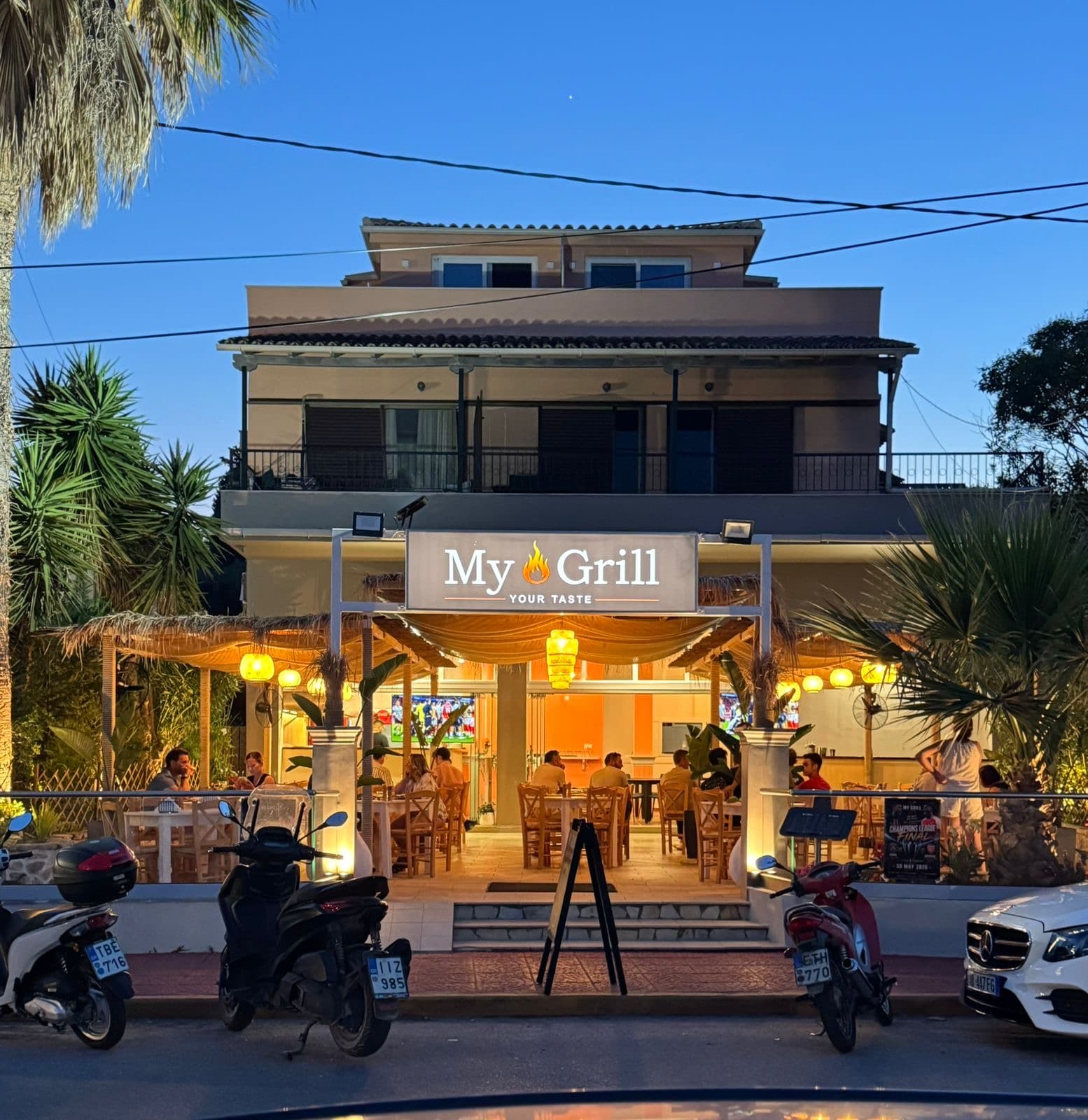 MyGrill Steakhouse lit up at dusk in Ipsos, Corfu