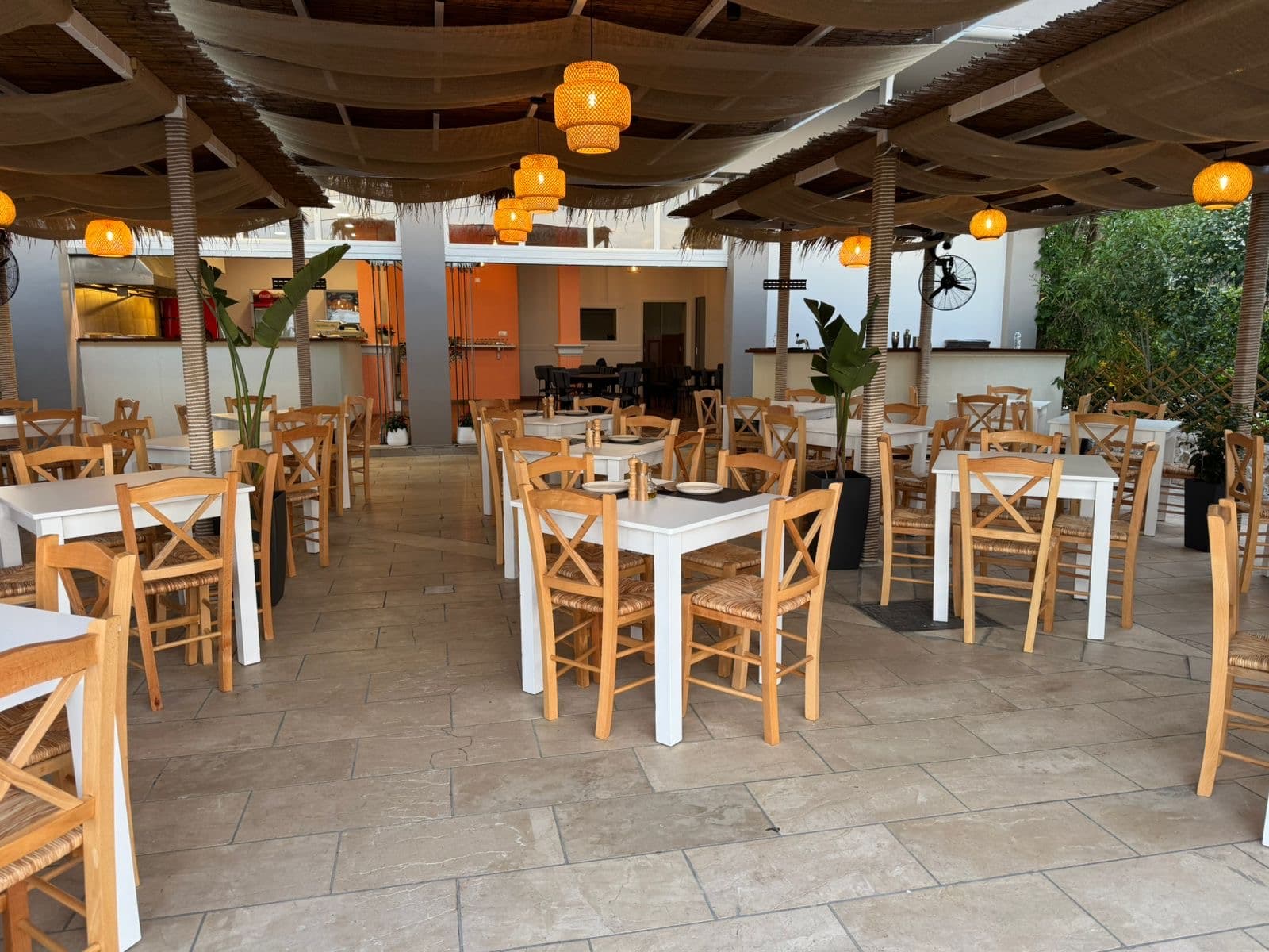 The covered terrace with wooden tables and rattan lanterns
